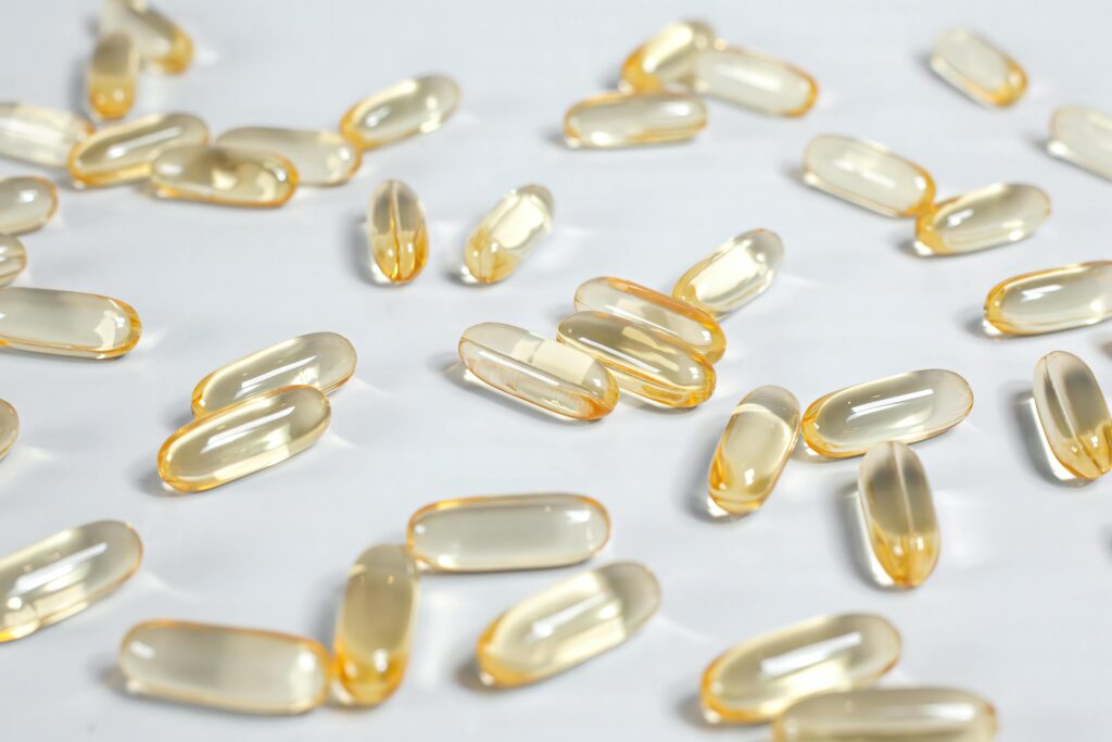 Close-up of yellow transparent softgel capsules on a white background, suitable for pharmaceutical or supplement themes.