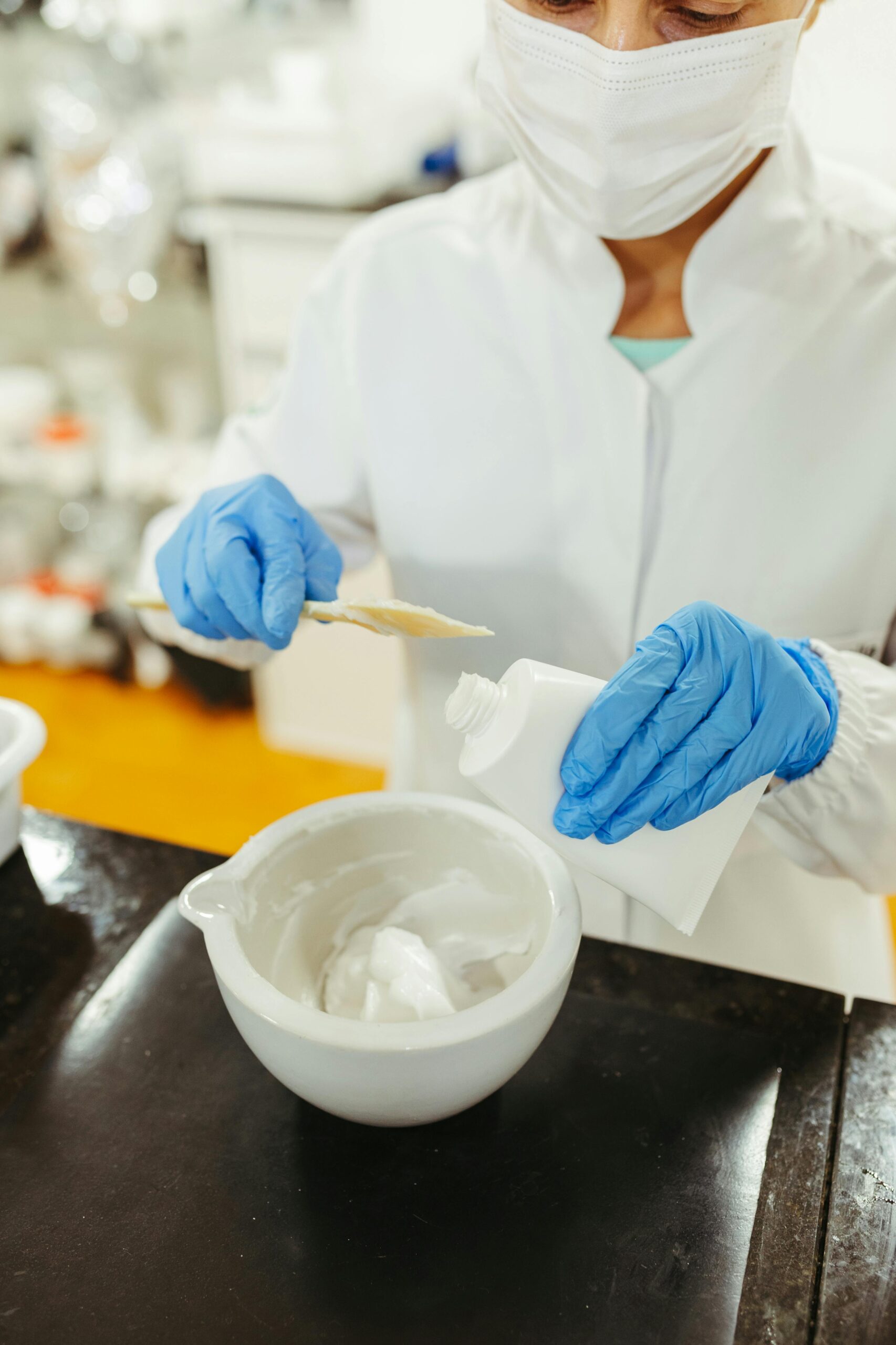 A scientist in a lab coat and mask blends chemical compounds for a research project.