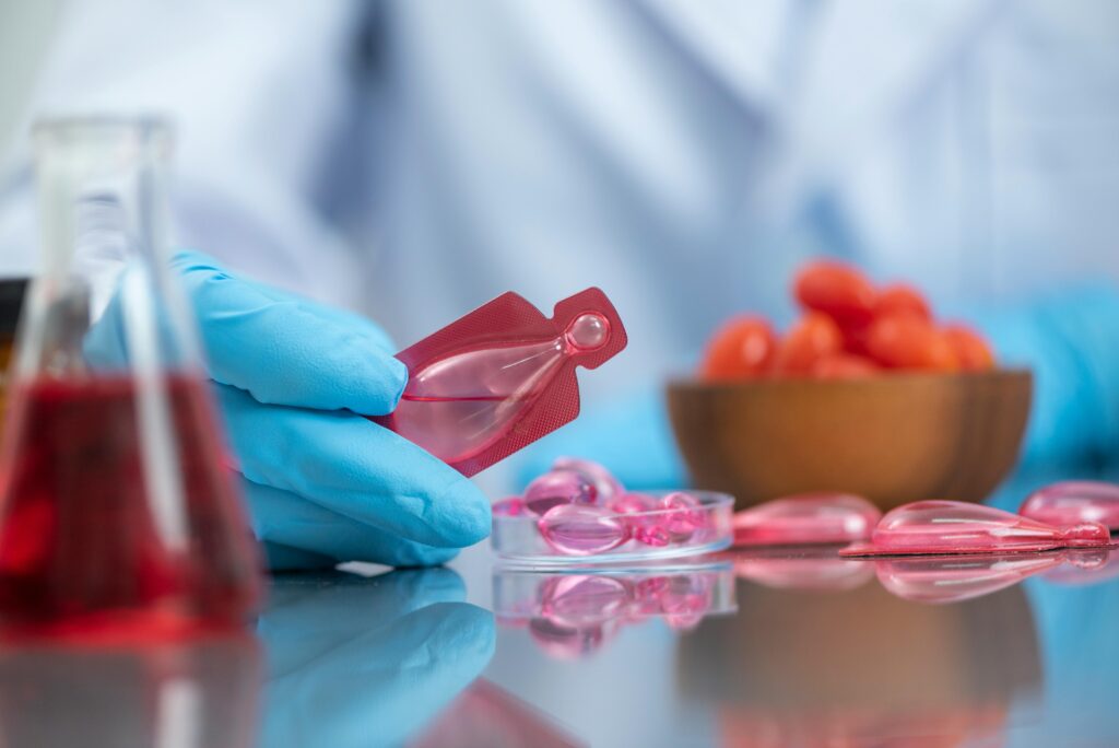 Scientist wearing gloves handling a red liquid vial in a laboratory setting, emphasizing research and medical care.
