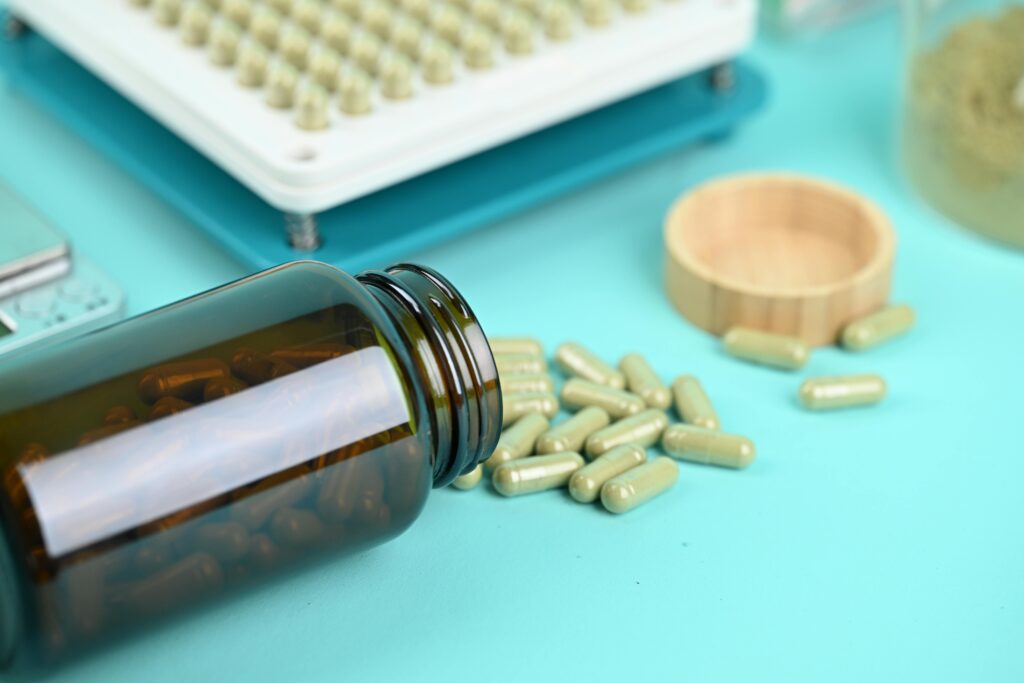 Pills and a capsule filling machine on a blue background, showcasing supplement production.
