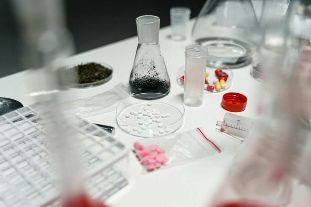 A laboratory table displaying pills, petri dishes, and chemical beakers for scientific research.