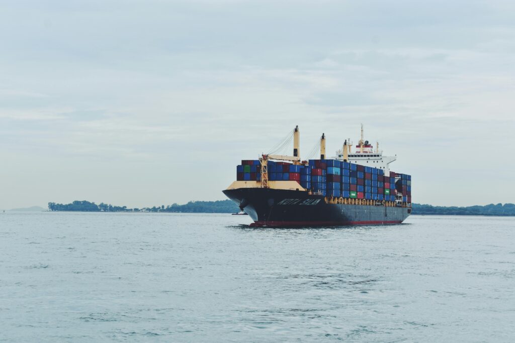 Large cargo ship transporting containers across a calm sea, symbolizing global logistics.