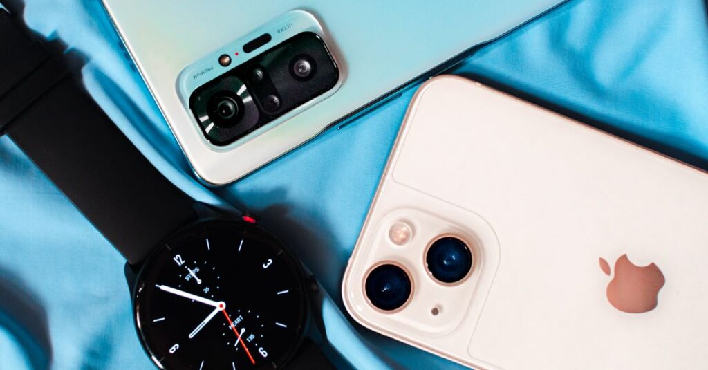 Close-up of smartphones and a smartwatch on blue fabric, showcasing technology essentials.