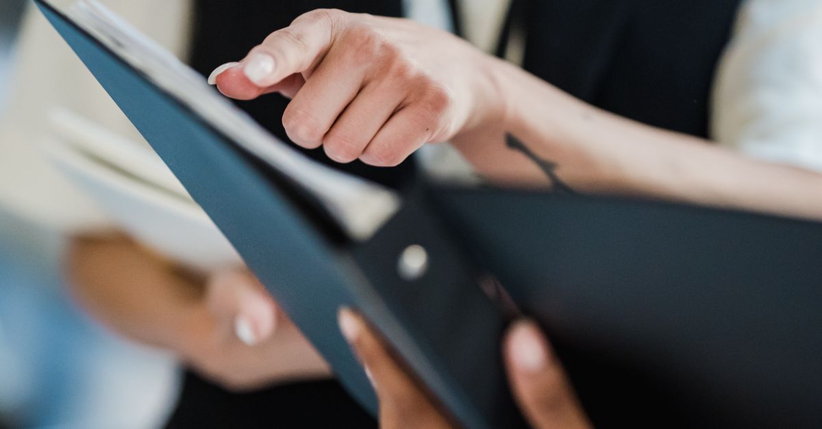 Two professionals pointing at documents during a collaborative office meeting.