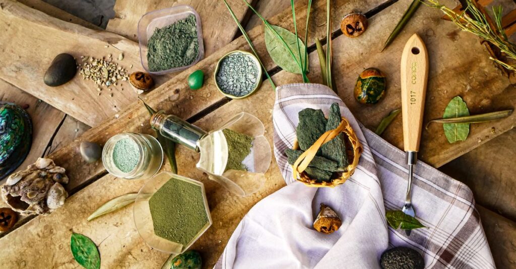Assortment of herbal powders and leaves on a rustic wooden table.