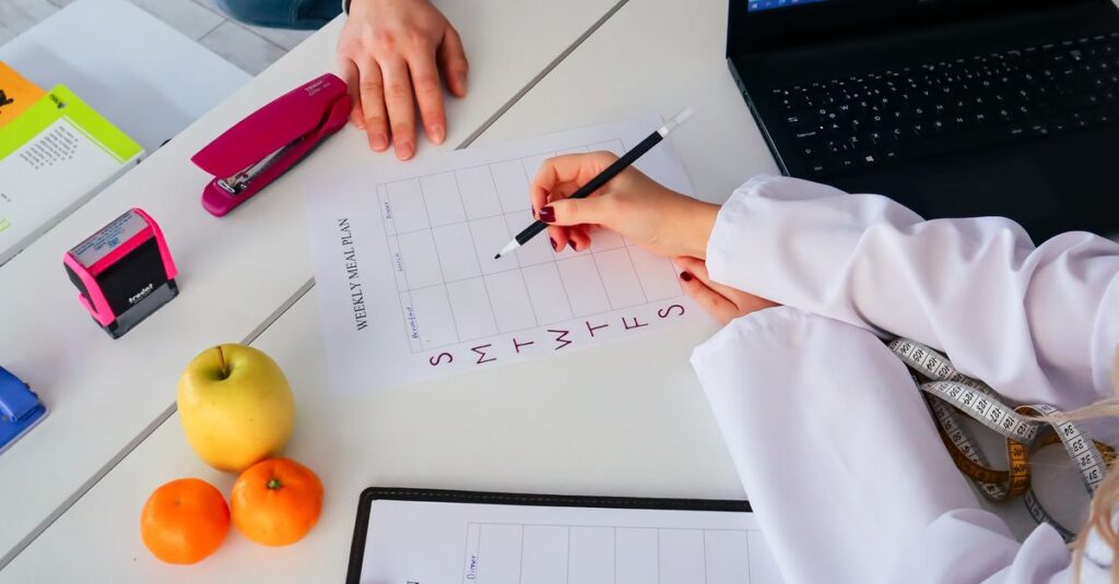 A nutritionist and a patient discuss a weekly meal plan in a modern office setting.