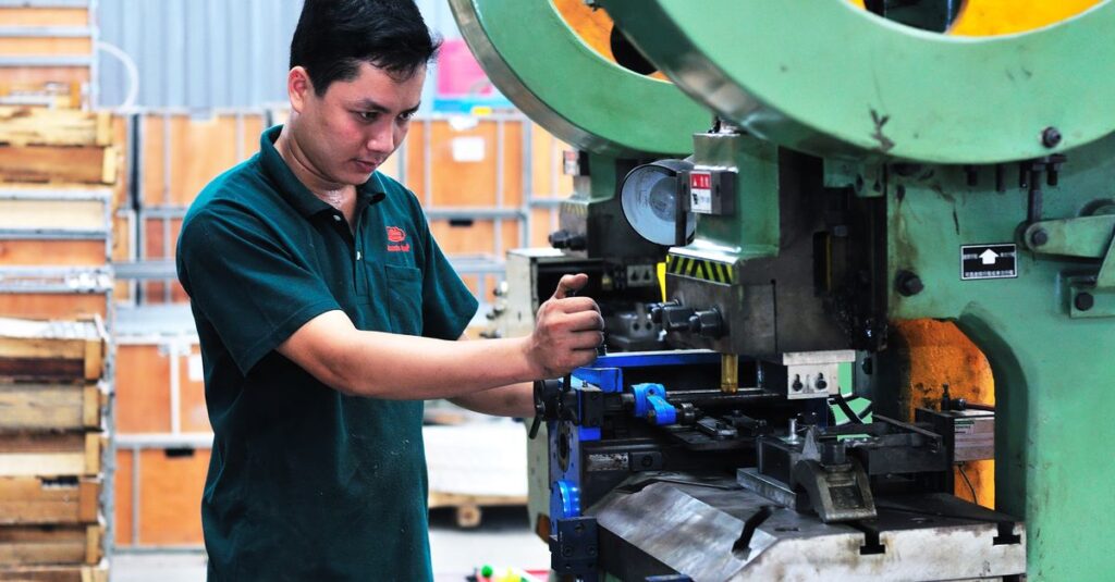 Man managing a machine in a factory setting, focusing on production.