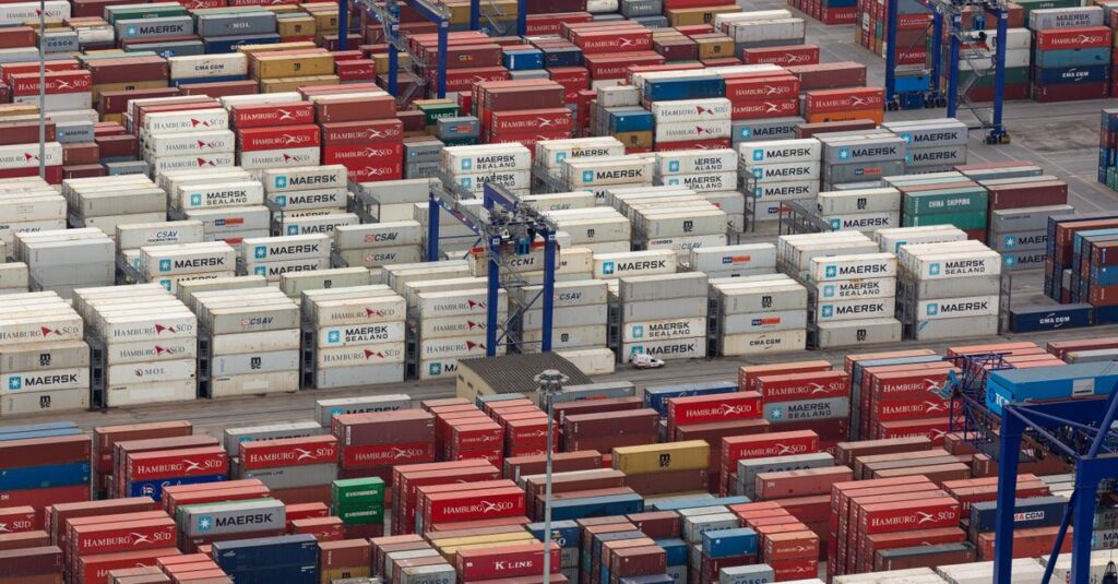 Aerial view of a bustling port with colorful cargo containers arranged in rows, showcasing logistics and trade.
