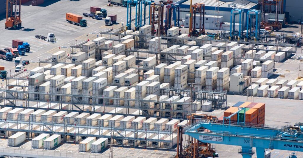 Bird's eye view of a logistics warehouse with shipping containers and trucks.