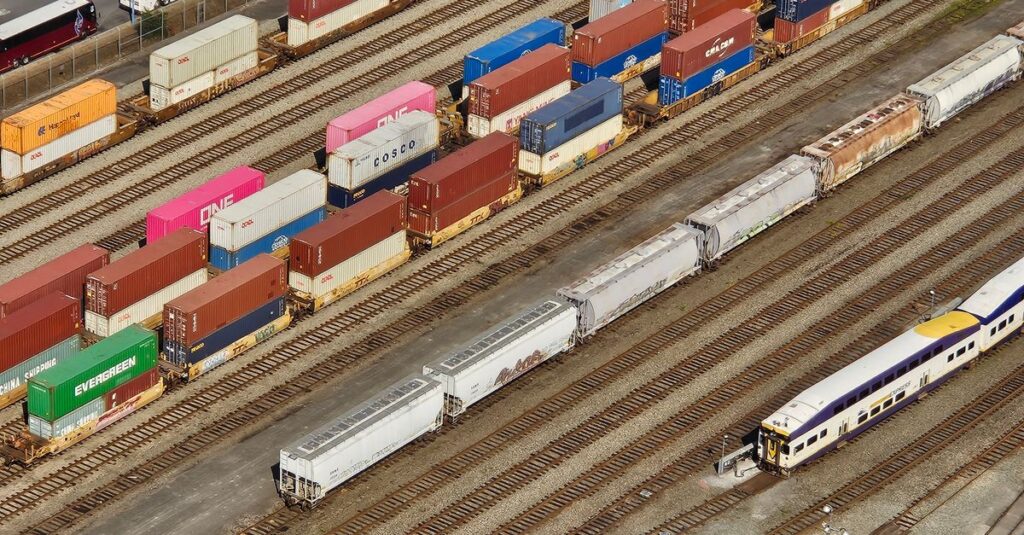 Aerial shot showcasing colorful freight containers on train tracks in a busy transportation yard.
