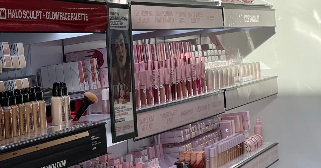 A well-organized makeup display in bright sunlight, showcasing various cosmetics on shelves.