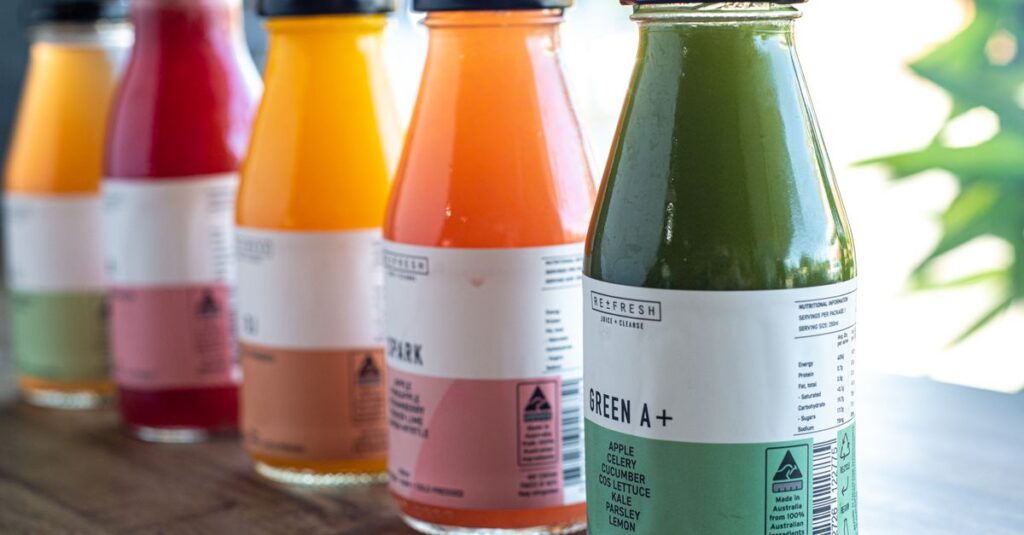 Assorted fresh bottled juices in vibrant colors on a wooden table, perfect for health enthusiasts.