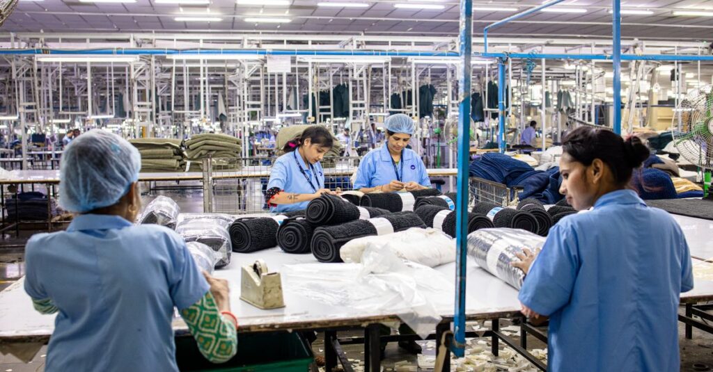 Blue-collar workers organize textiles in a busy factory setting.