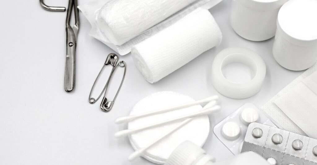 A detailed flat lay of essential first aid supplies including bandages, scissors, and pills.