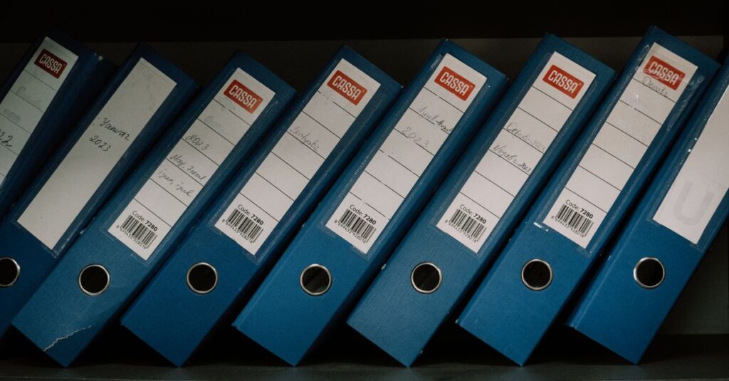 Neatly arranged blue office binders labeled with dates and names for organized storage.