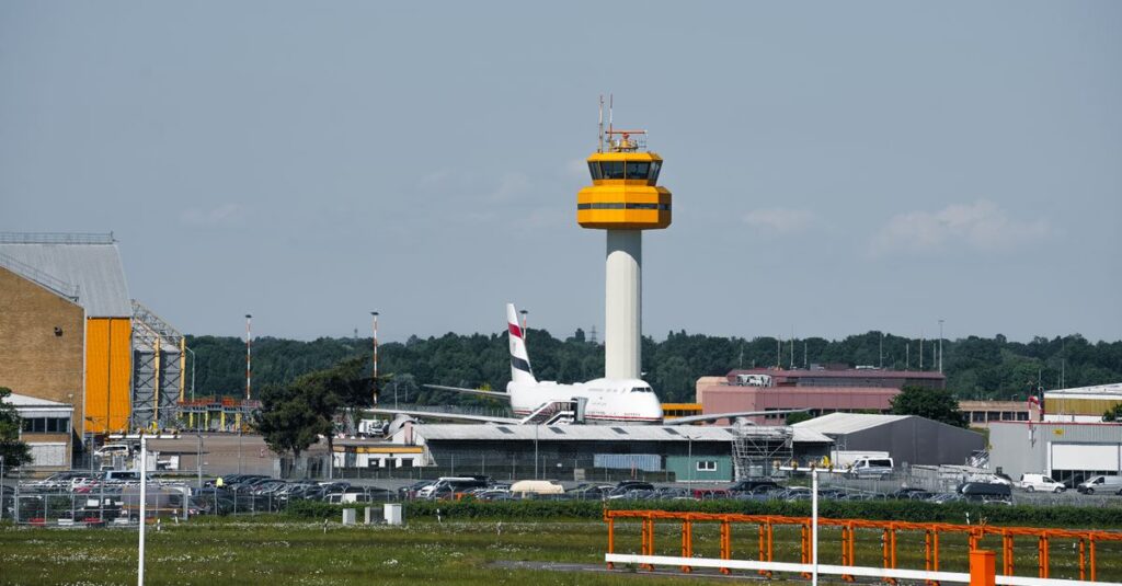 View of a control tower and airplane at Hamburg Airport on a sunny day.