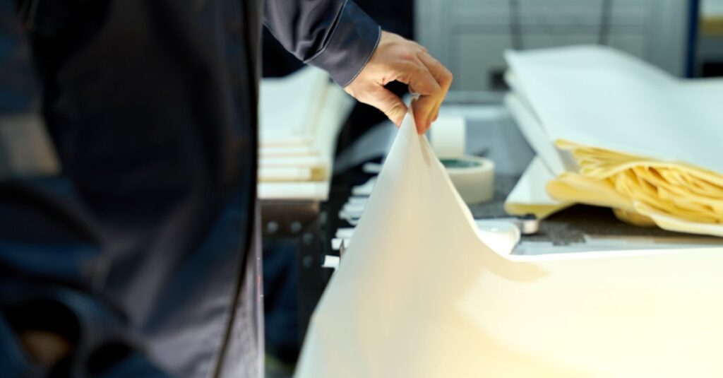 An industrial worker manages large sheets in a manufacturing setting, focusing on precision and quality.