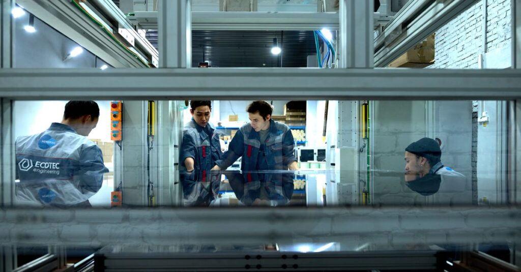 Engineers collaborate over advanced machinery in a high-tech indoor workspace.
