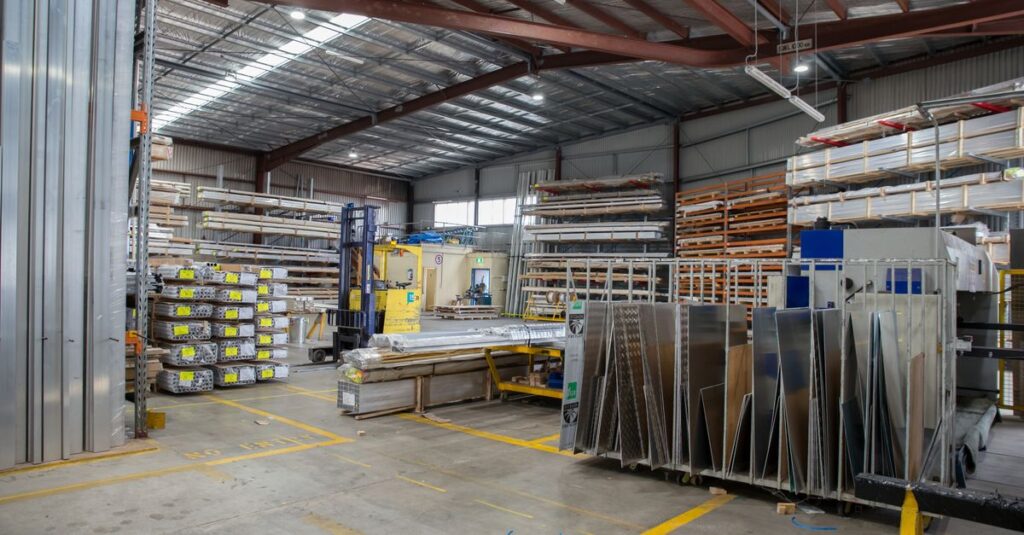 Wide view of an industrial warehouse interior showcasing stacks of steel and metal sheets.