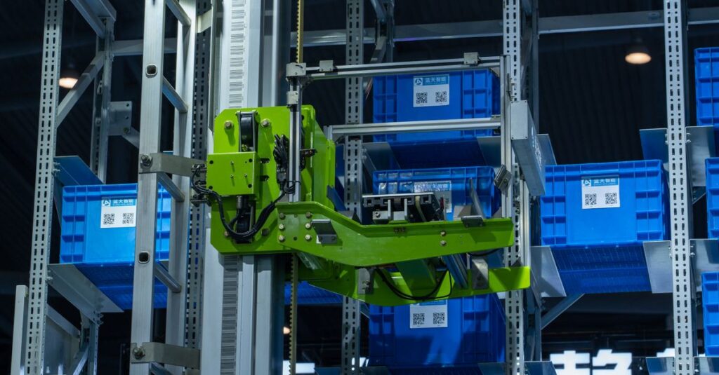 High-tech automated warehouse system featuring a green robotic arm handling blue storage crates.
