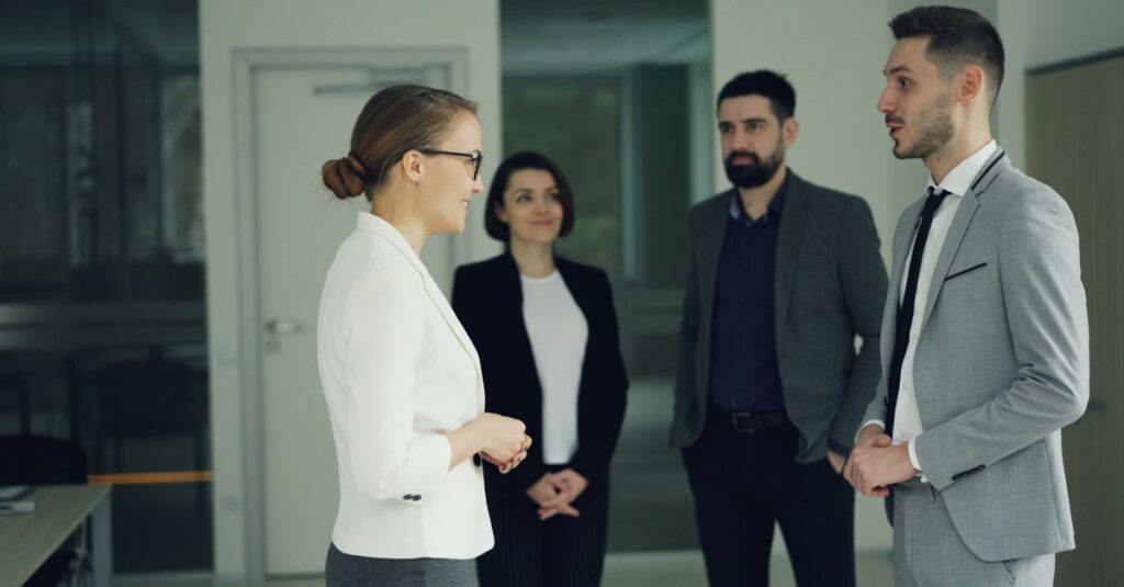 Group of professionals in formal attire having a discussion in a modern office setting.