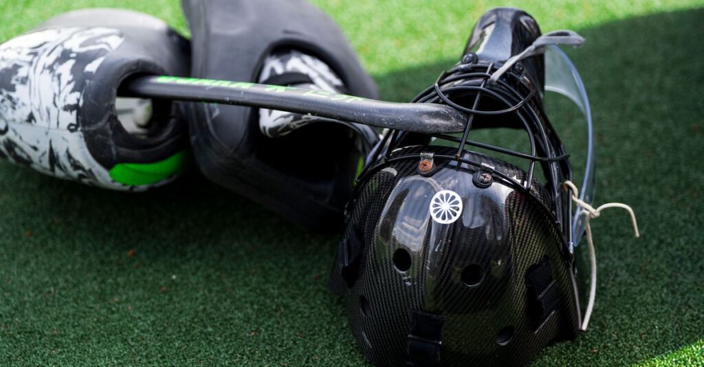 Catcher's helmet and pads on artificial turf, standard baseball equipment.