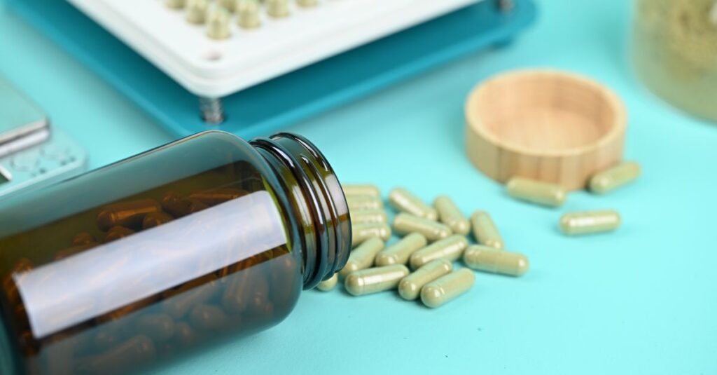 Pills and a capsule filling machine on a blue background, showcasing supplement production.