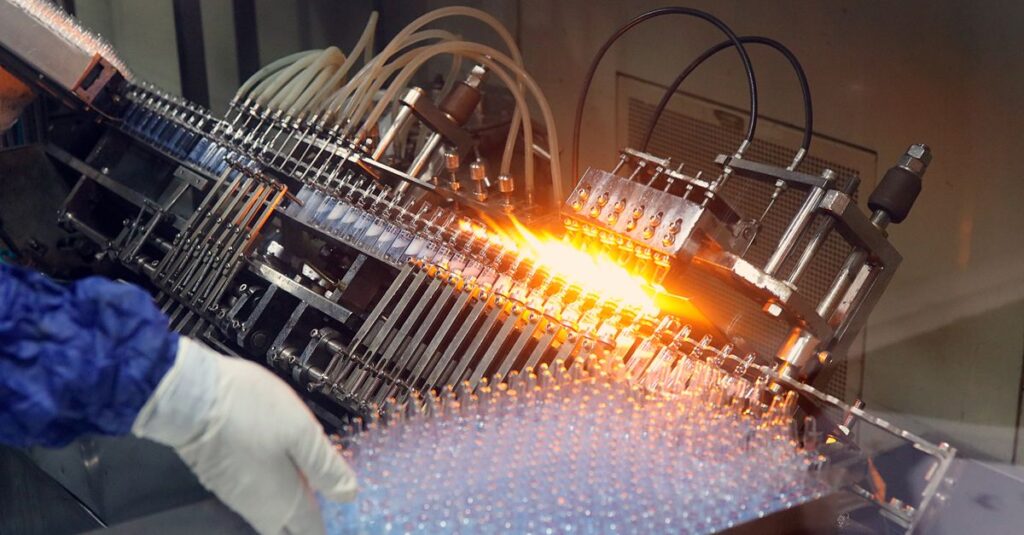 Close-up of ampoule filling and sealing in a pharmaceutical manufacturing line.