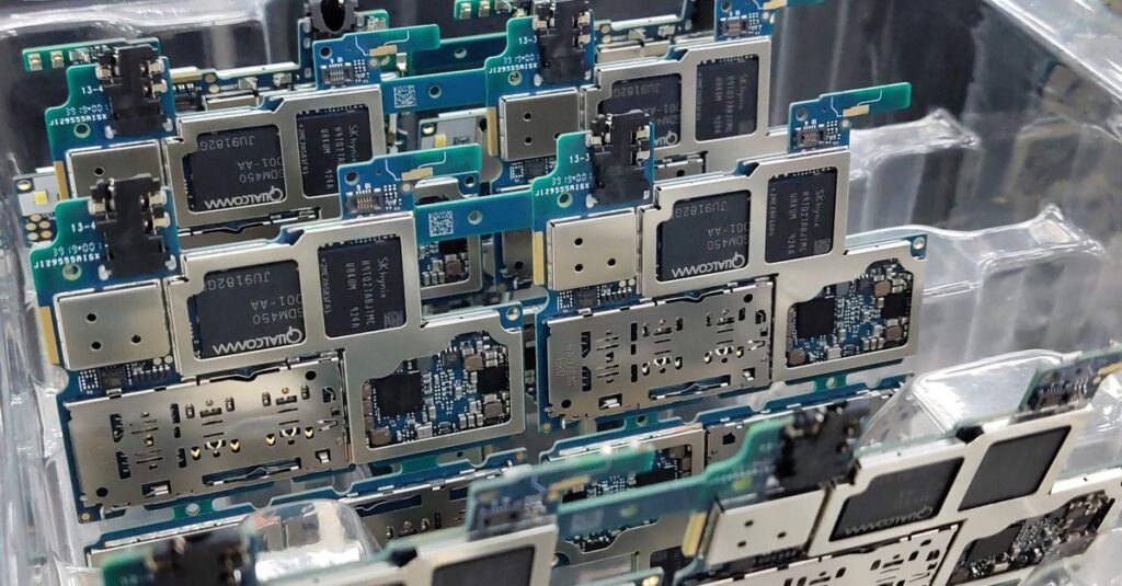 From above of circuit boards of modern smartphones placed in plastic box in electronics factory