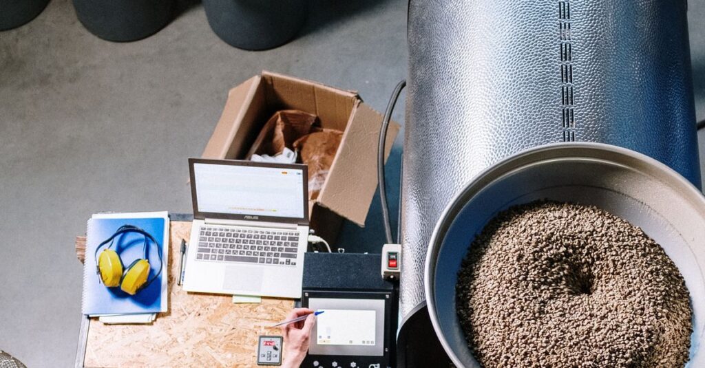 An overhead view of a man operating a coffee roaster in an industrial setting.