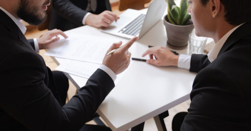 Three businessmen engaged in discussion during a formal meeting in an office setting.