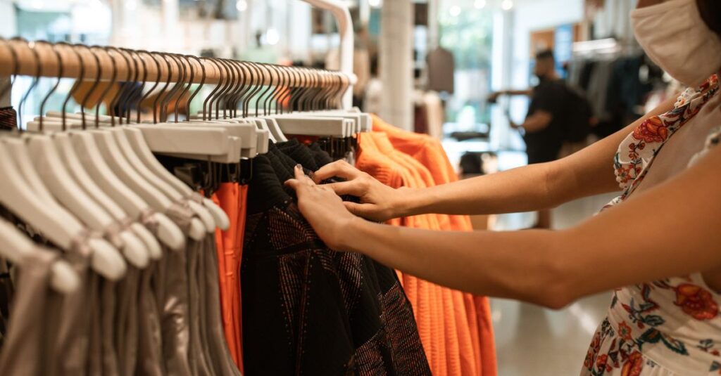 A woman shops for clothes in a store while wearing a face mask, highlighting the new normal.
