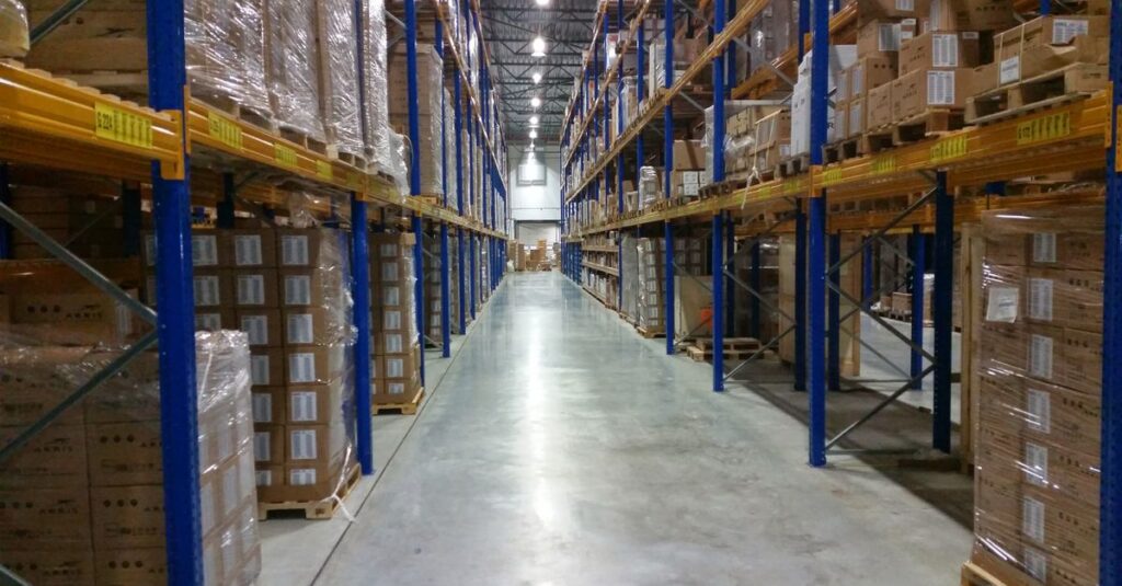 Interior view of a large warehouse aisle lined with stacks of organized cardboard boxes.