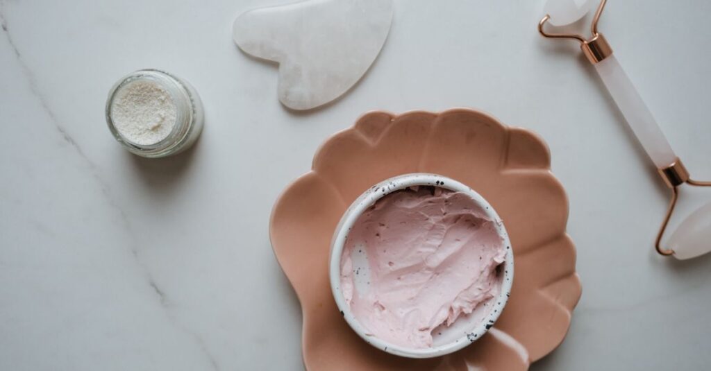 Elegant top view of skincare essentials including cream, gua sha, and roller on marble surface, perfect for beauty concepts.
