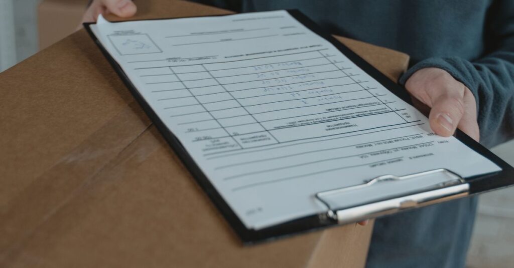 Person in a warehouse holding a box with a shipping checklist on a clipboard.