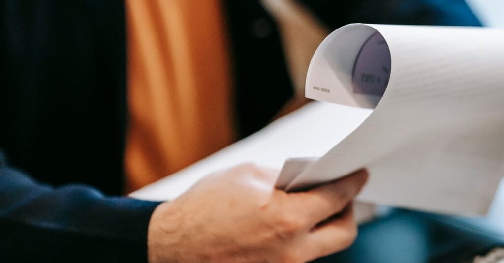 Business professional reviewing important documents indoors. Hands focus, blurred background.