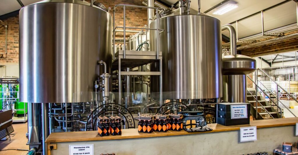 Interior of a brewery showcasing large stainless steel tanks and bottled beverages on display.