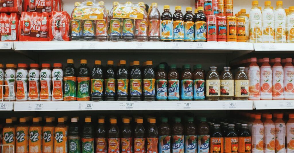 Rows of colorful plastic bottles with lemonades placed on light shelves in supermarket