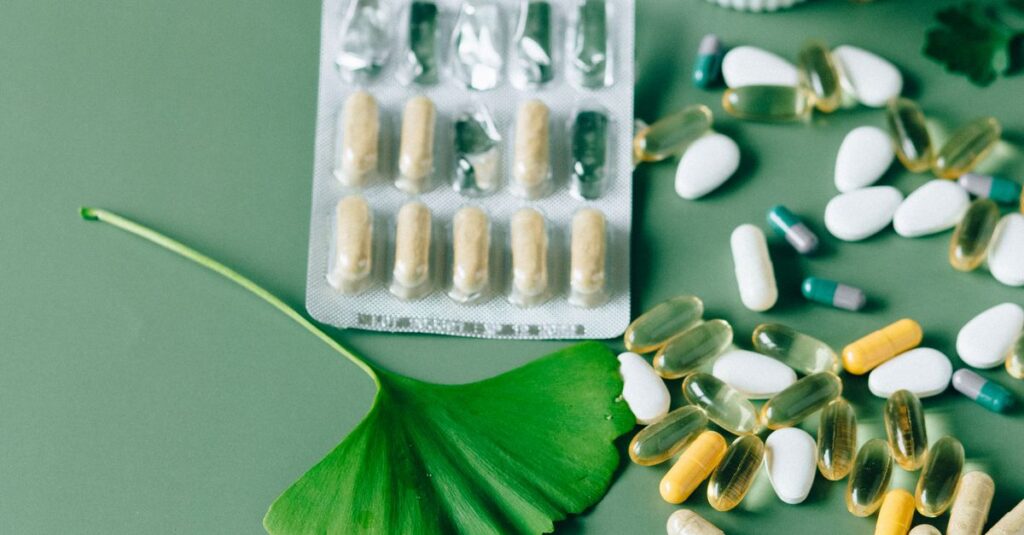 A flat lay of various natural supplements and capsules with herbs on a green surface.