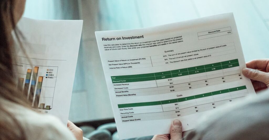 Close-up of two individuals analyzing financial documents related to return on investment.