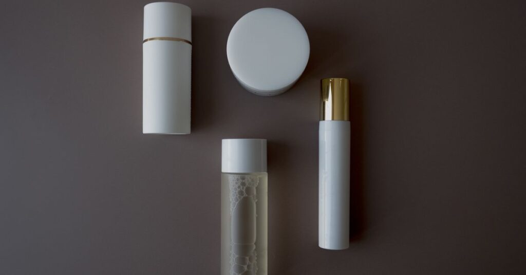 Top view of various skincare bottles and flasks on a sleek gray background.