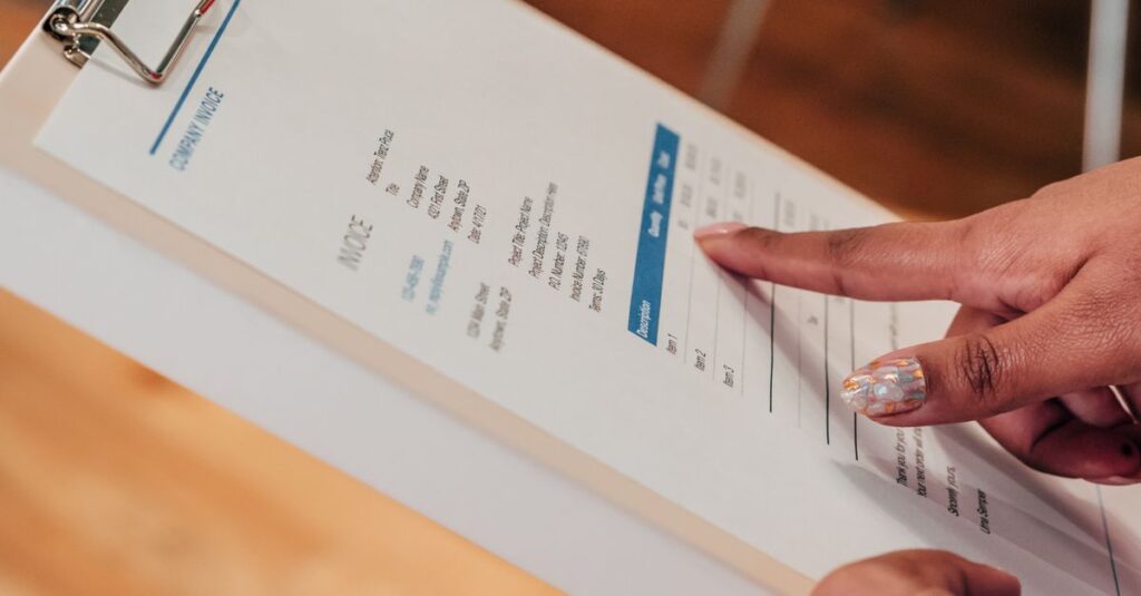 Close-up image of a person pointing to a document on a clipboard, indoors.