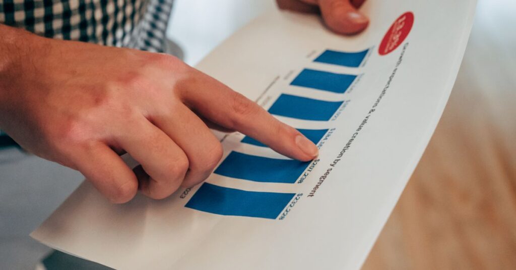 Close-up of hands pointing at a bar chart on paper, analyzing financial stats and report.