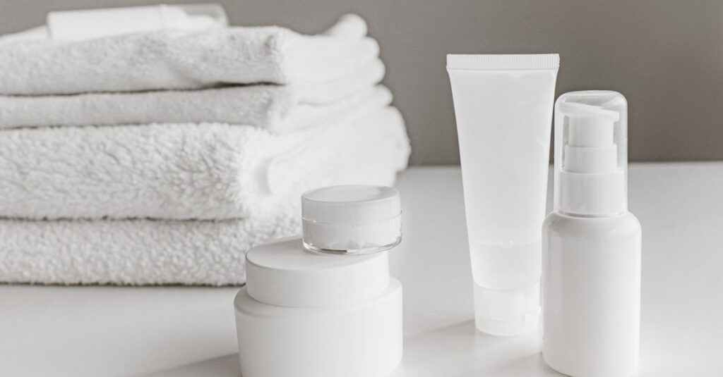 Minimalist arrangement of white skincare products and towels for a modern aesthetic.