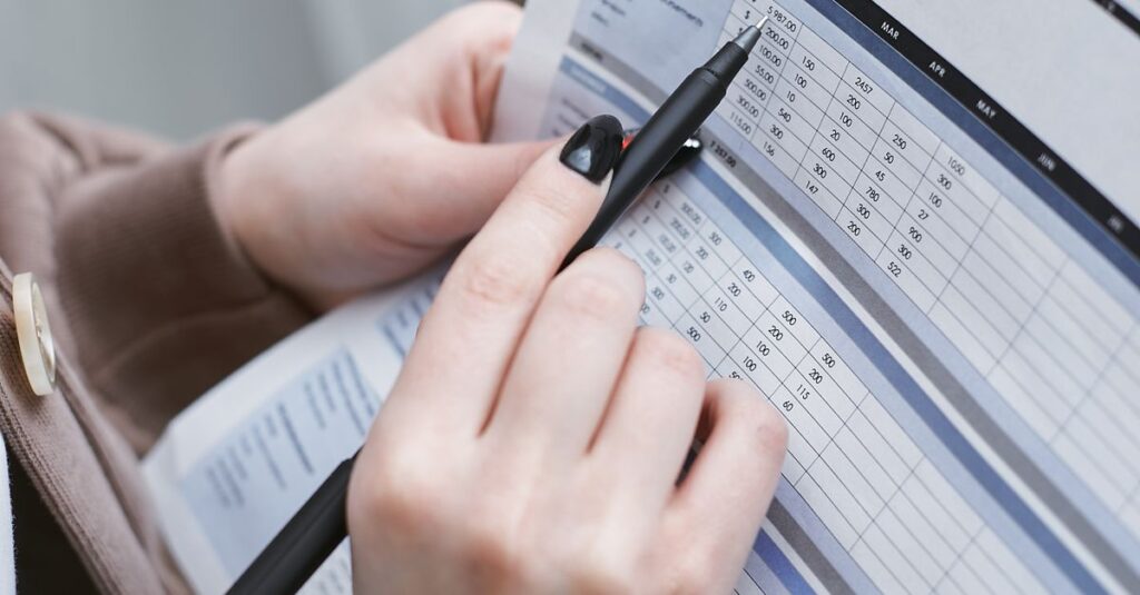 Hands holding a pen review a family budget document with graphs and tables.