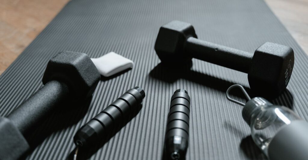 Close-up of dumbbells, jump rope, and water bottle on a yoga mat, ideal for home fitness routines.