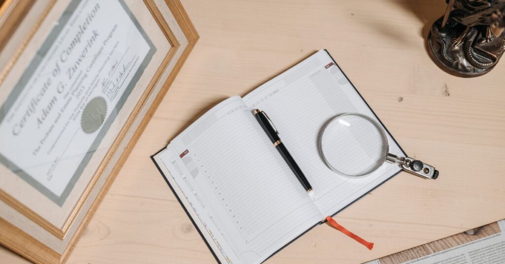 A tidy workspace featuring a certificate, open journal, magnifier, and statue on a wooden desk.