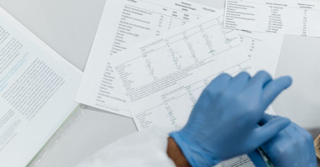 Close-up of gloved hands reviewing printed lab test results on a white surface.