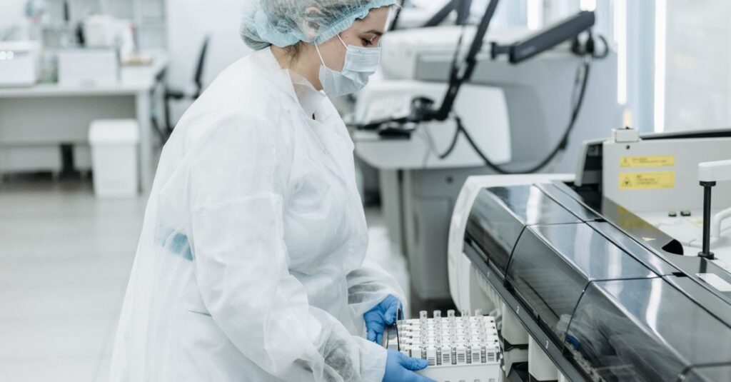 Laboratory scientist in protective gear working with medical samples.