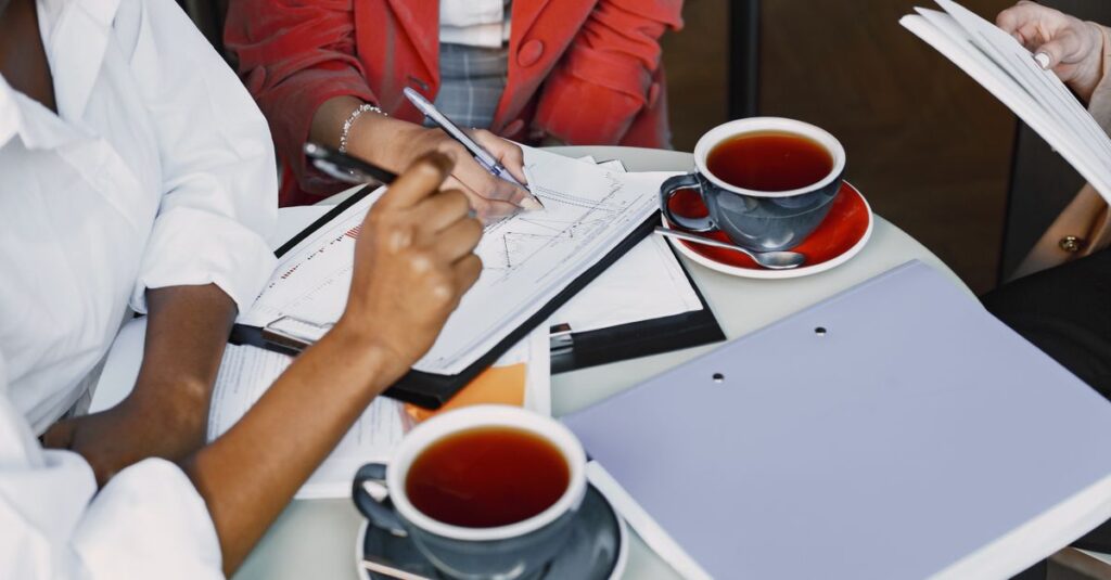 Business professionals collaborating over coffee and documents in a modern setting.